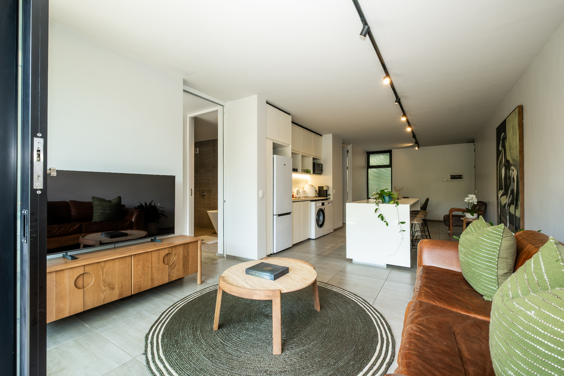 Wide living room view with leather sofa, TV and kitchen island